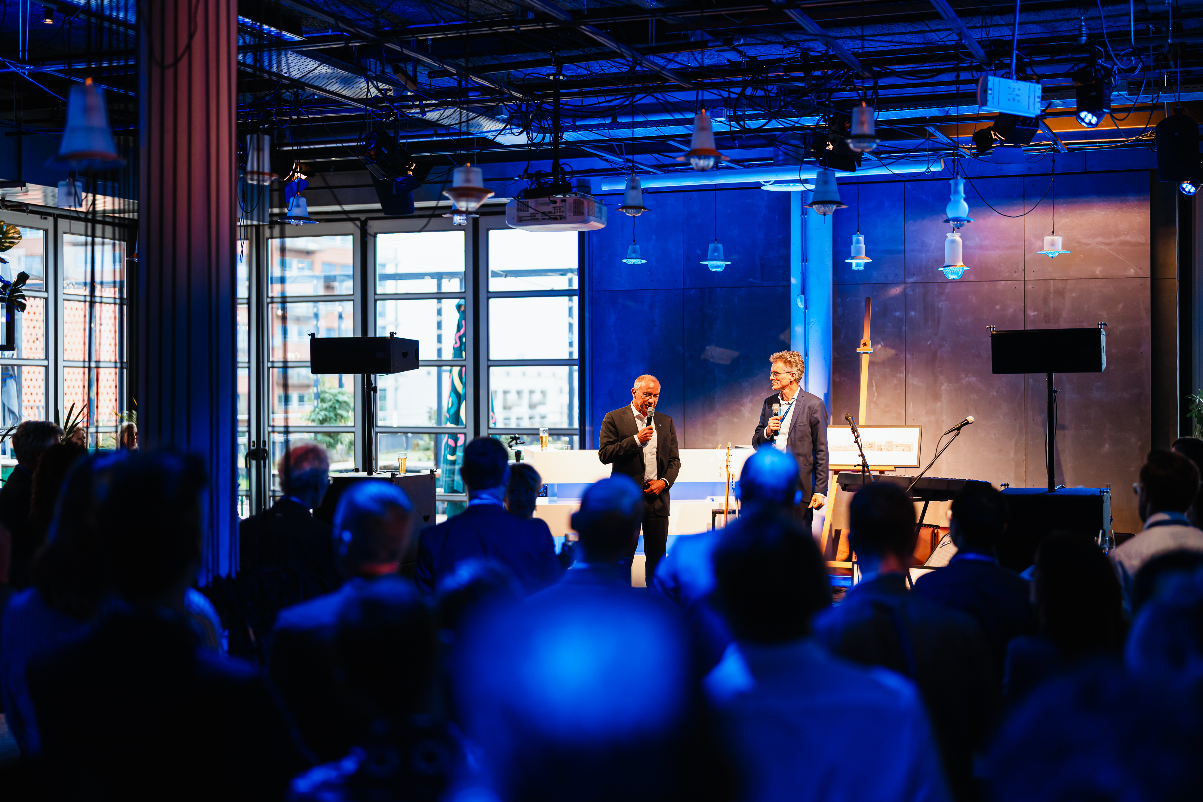Two people standing on stage with a large crowd