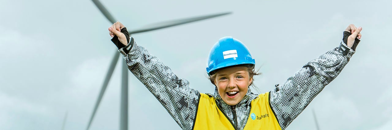 Happy girl in front of a wind turbine