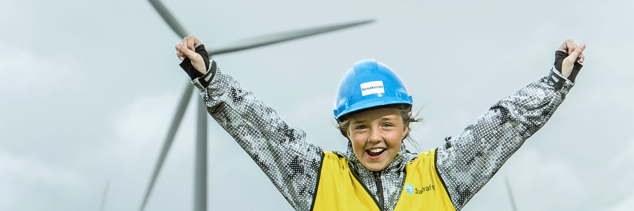 Happy girl in front of a wind turbine